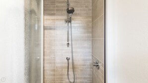 Douche met een handdouche en een vaste douchekop, beide bevestigd aan een betegelde muur.