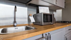 Een keuken met een roestvrijstalen spoelbak, een magnetron en een fornuis.