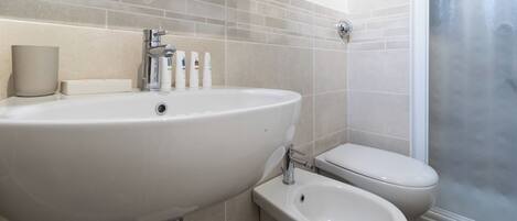 A bathroom with a large sink, a toilet, and a bidet.