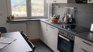 Una cucina moderna con vista su un paesaggio boschivo, un'area pranzo con tavolo e sedie, e un forno integrato.