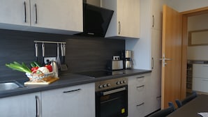 Una cucina moderna con elettrodomestici in acciaio inossidabile, un forno a microonde, una macchina da caffè e un'area pranzo con tavolo e sedie.