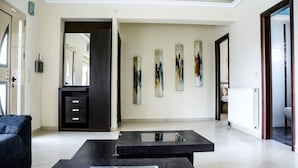 Un salon moderne avec une table basse en bois foncé, un canapé noir et des œuvres d’art abstraites accrochées au mur.