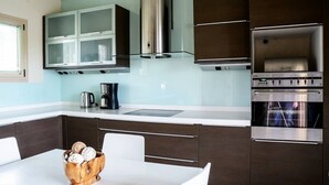 Une cuisine moderne avec des meubles de couleur sombre, des appareils en acier inoxydable et un plan de travail blanc.