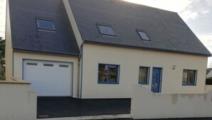 A two-story house with a garage, a front door, and a driveway. - FREHEL HOUSE (Fréhel)