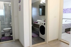 A compact bathroom with a toilet, washing machine, and sink.