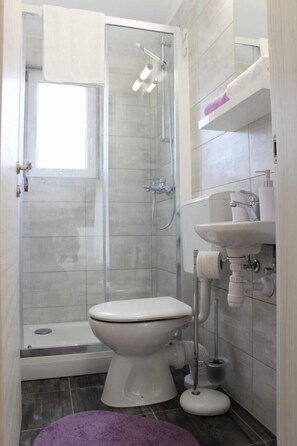 A bathroom with a shower, toilet, and sink.