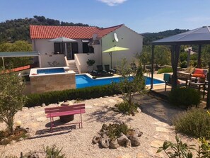 A house with a swimming pool, outdoor seating, and a pergola.