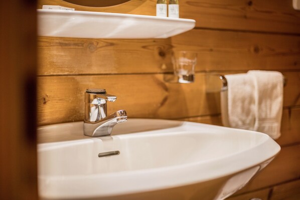 Un baño con un lavamanos blanco, un espejo y paredes de madera.