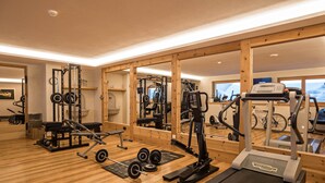 A gym with exercise equipment, a treadmill, and a mirrored wall.