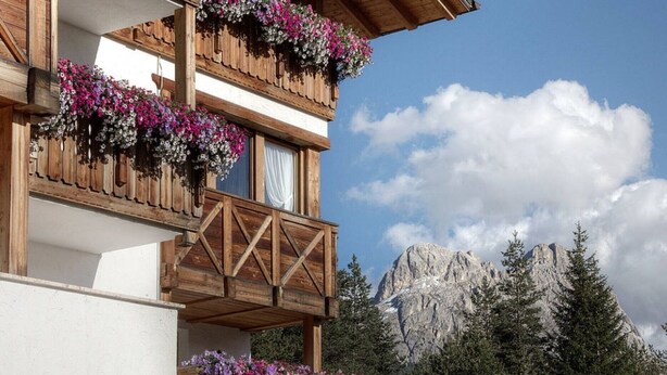 Un bâtiment en bois doté de balcons ornés de fleurs, se dressant sur un fond de montagnes.