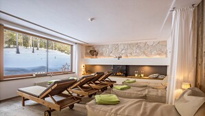 Une pièce avec une cheminée, des fauteuils confortables et une vue sur un paysage enneigé.