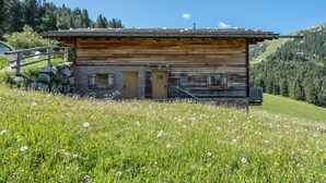 Eine Blockhütte mit steinernen Fundament, Holztüren und einer kleinen Veranda.