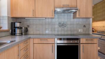 A modern kitchen with wooden cabinets, a stainless steel oven, and a coffee maker.