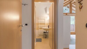 A narrow hallway leading to a bathroom with a sink, towel rack, and a small trash bin. - Apartment “Thymian - Thalerhof” with Mountain View, Wi-Fi, Balcony & Garden (Eggen/Deutschnofen)