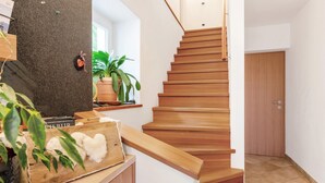 A wooden staircase leading to a room with a door, a potted plant, and a shelf with items. - Apartment “Thymian - Thalerhof” with Mountain View, Wi-Fi, Balcony & Garden (Eggen/Deutschnofen)