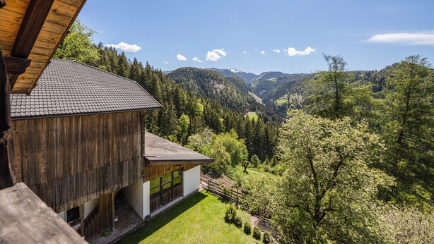 A wooden cabin with a view of a forested valley and mountains. - Apartment “Thymian - Thalerhof” with Mountain View, Wi-Fi, Balcony & Garden (Eggen/Deutschnofen)