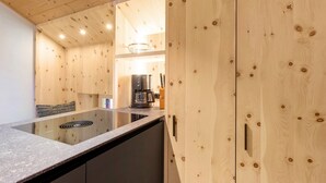 Moderni keittiö, jossa on puiset kaapit, sisäänrakennettu liesi ja kahvinkeitin.