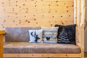 A wooden cabin interior with a sofa and three decorative pillows.