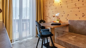 Ein Essbereich mit einem Holztisch, zwei Stühlen, einer Couch und einer Holzwand mit einer Leuchte.