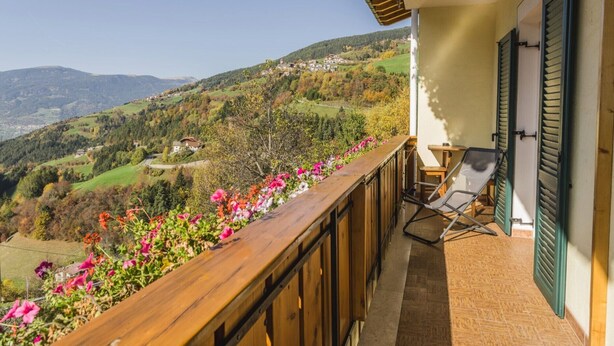 Ein Balkon mit Blick auf eine hügelige Landschaft, ein Stuhl und ein Tisch.