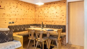 Ein gemütliches Zimmer mit einer Holzwand, einem Sofa, einem Esstisch mit Stühlen und einer Tür.