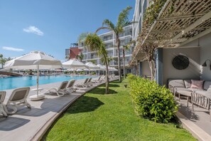 A poolside area with lounge chairs and umbrellas, a small garden, and a building with balconies. - Barut GOIA - All Inclusive (Manavgat)