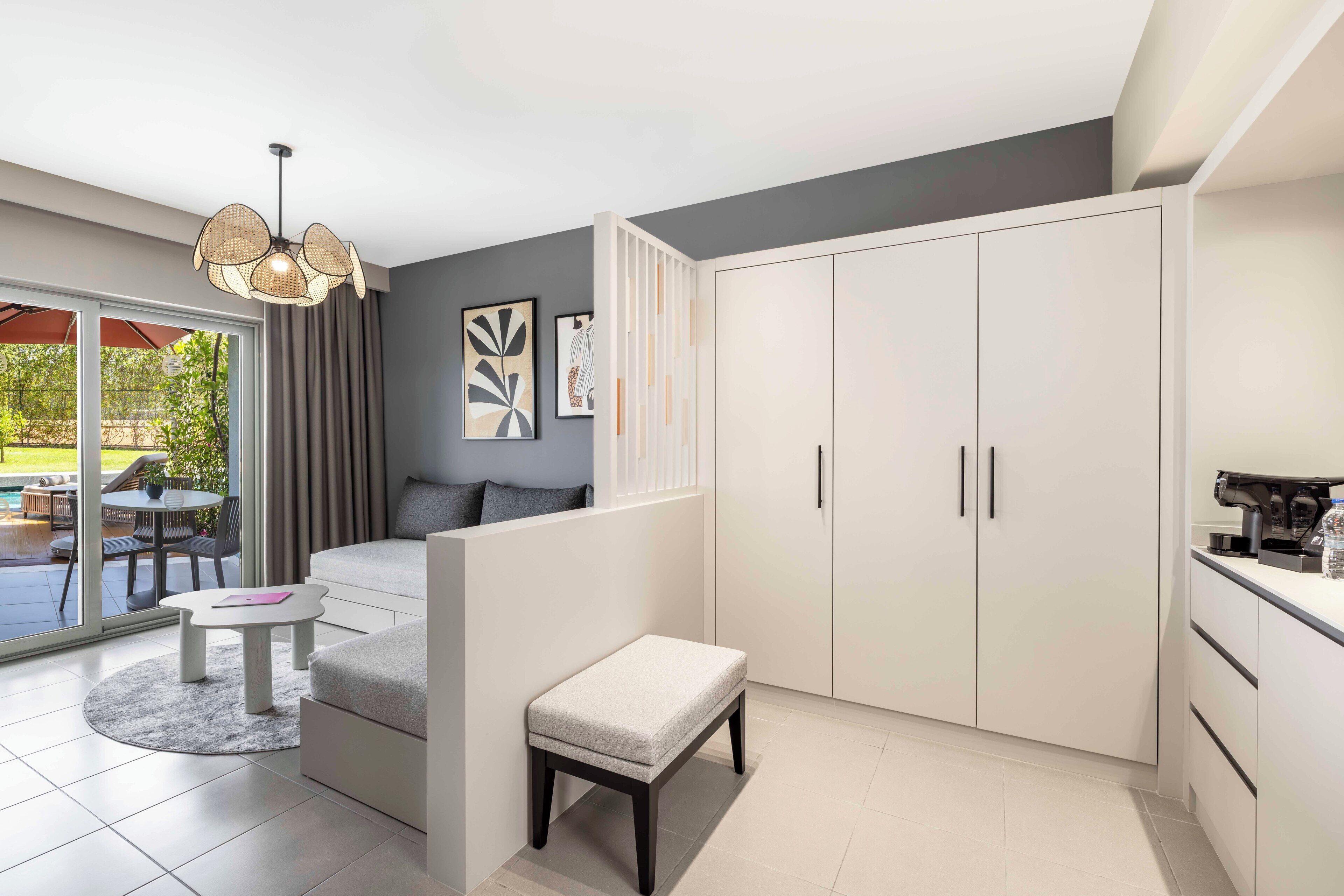 A modern living room with a sofa, a small table, a bench, and a large wardrobe.