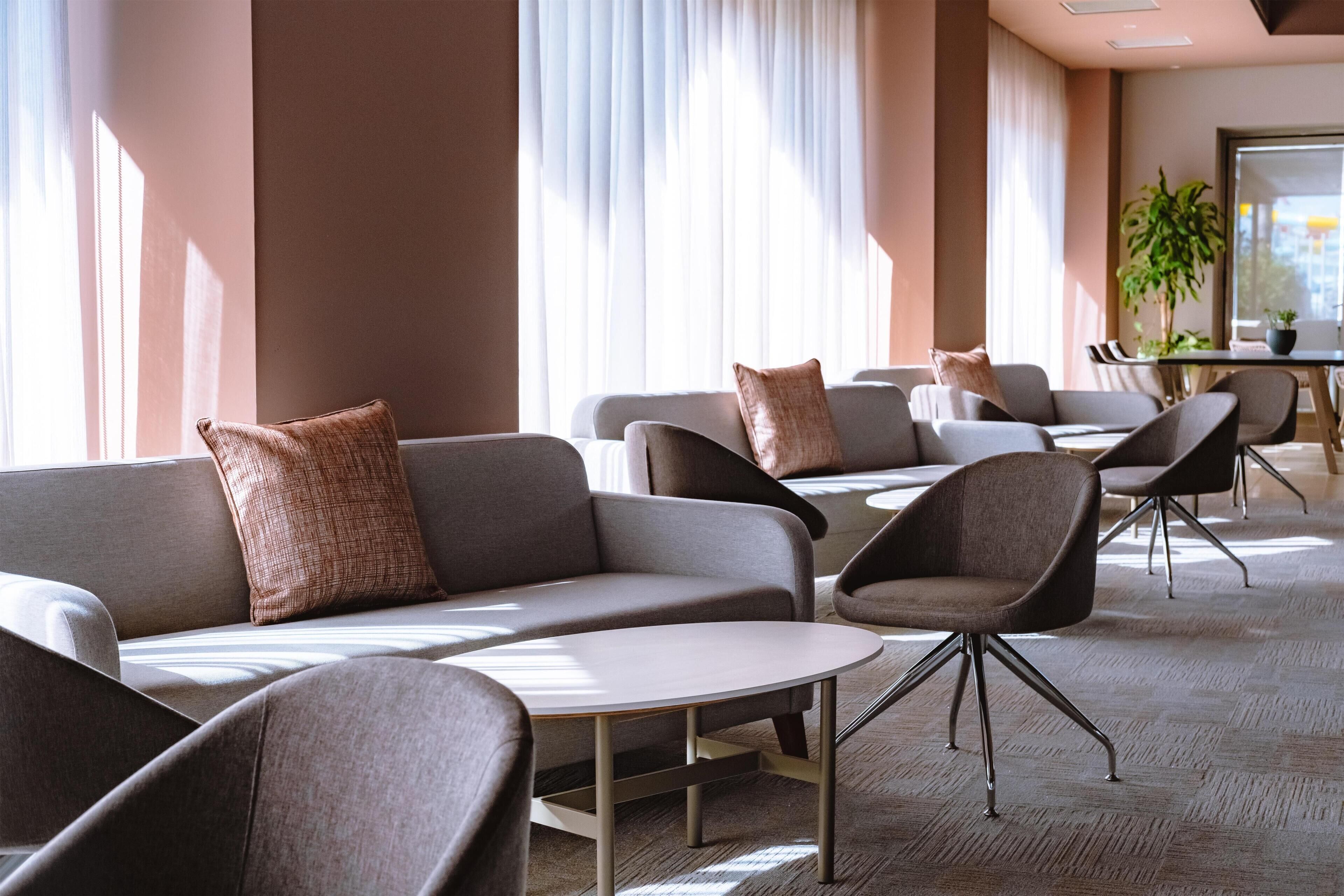 Um hall de hotel moderno com sofás, cadeiras e uma pequena mesa.