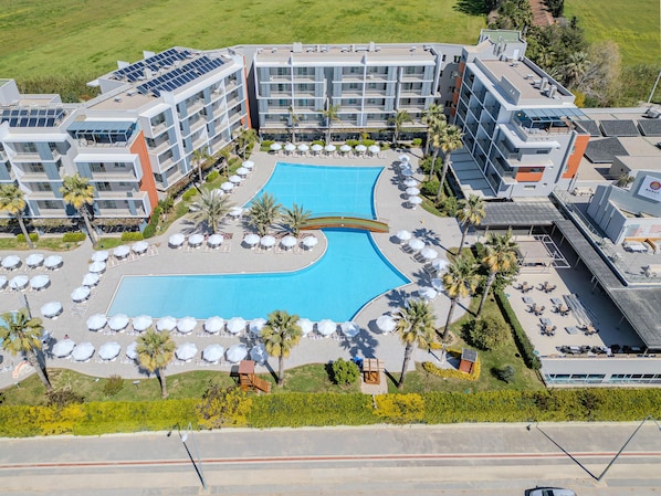 A hotel with a central swimming pool, multiple balconies, and outdoor seating areas. - Barut GOIA - All Inclusive (Manavgat)