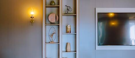 A modern living room with a bookshelf, a mounted TV, and a wall-mounted light fixture.