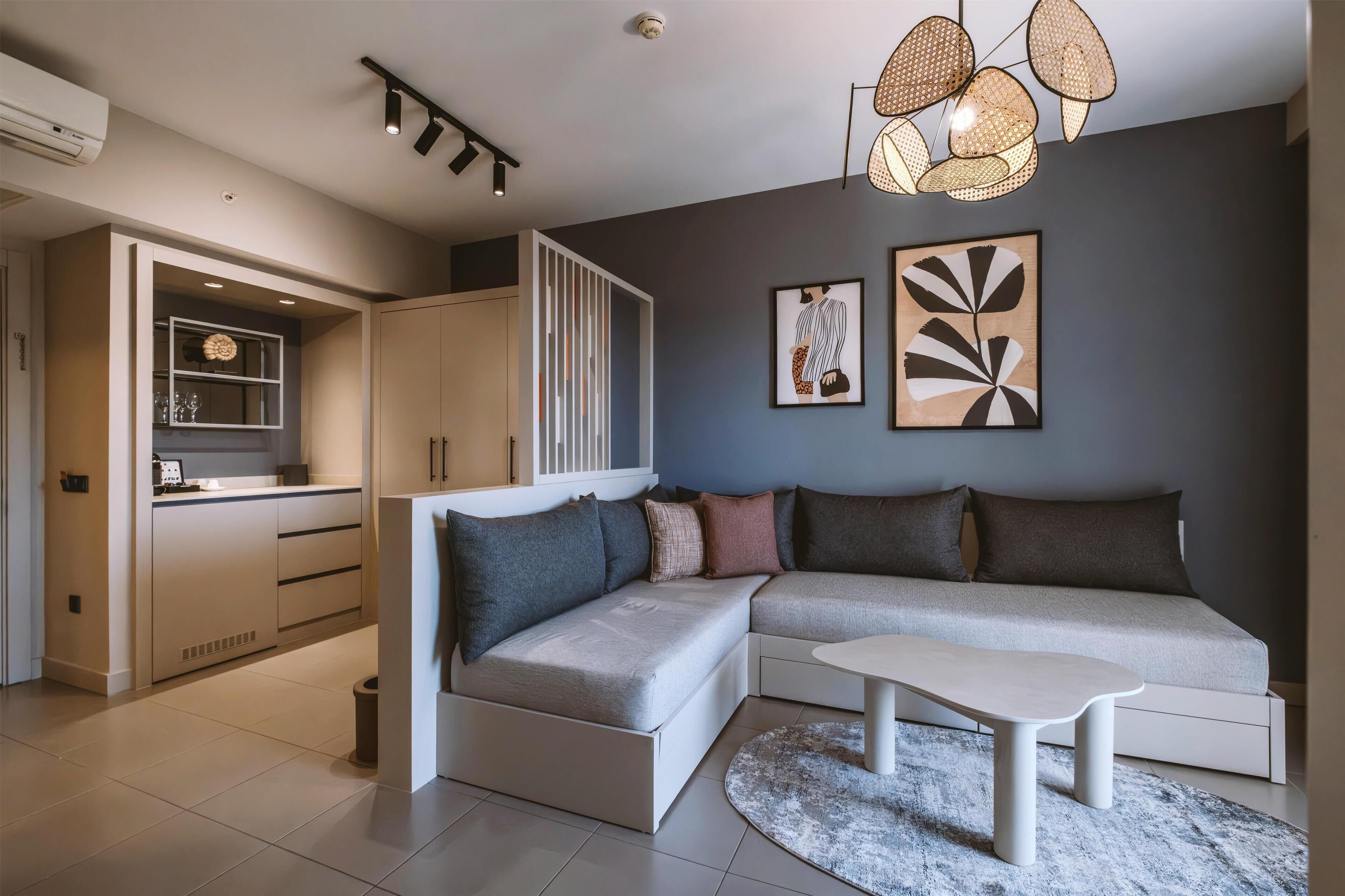 Una sala de estar moderna con un sofá modular, una mesa de comedor y una cocina con armarios y encimera.