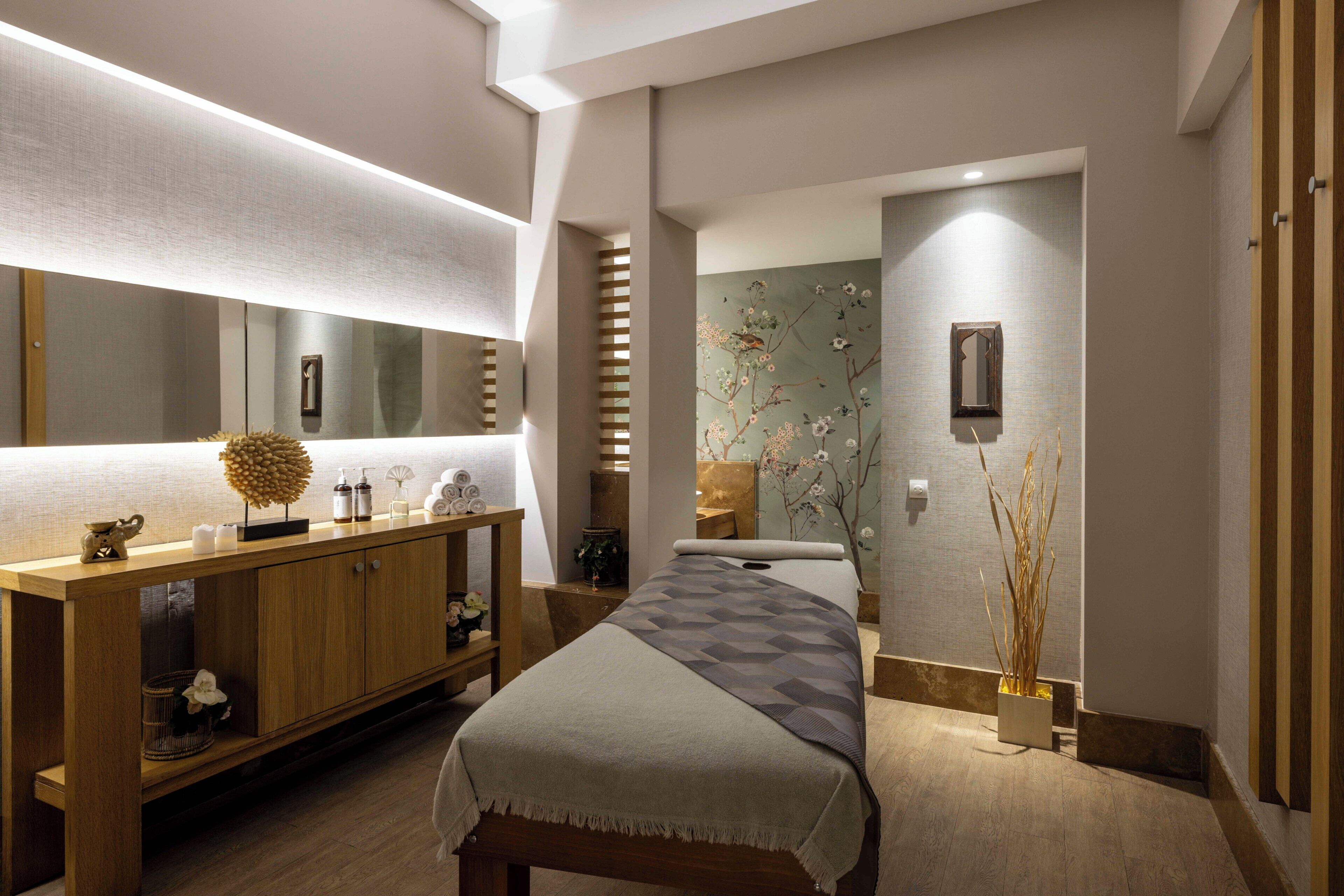 A modern bedroom with a wooden dresser, a bed with a patterned bedspread, and a large mirror above the dresser.