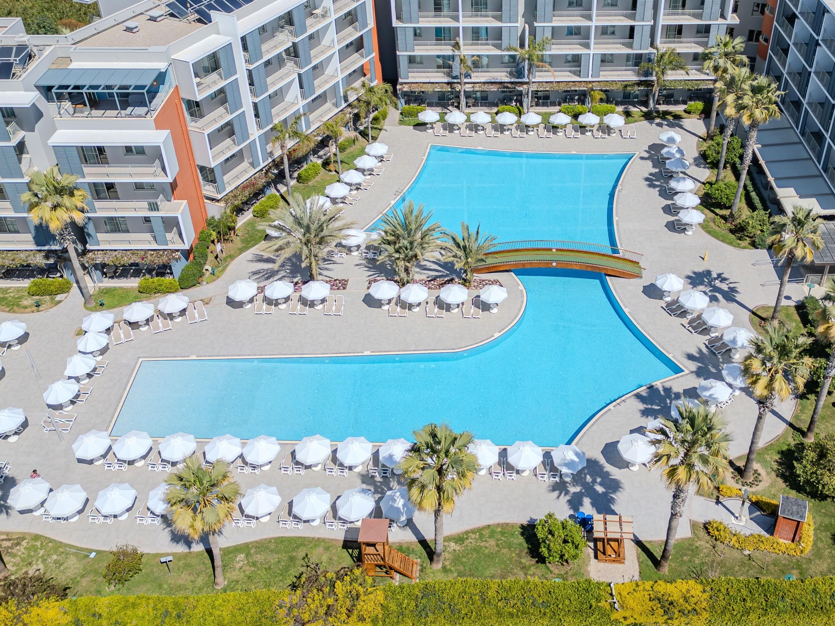 A large, rectangular swimming pool with multiple lanes, surrounded by sun loungers and umbrellas.