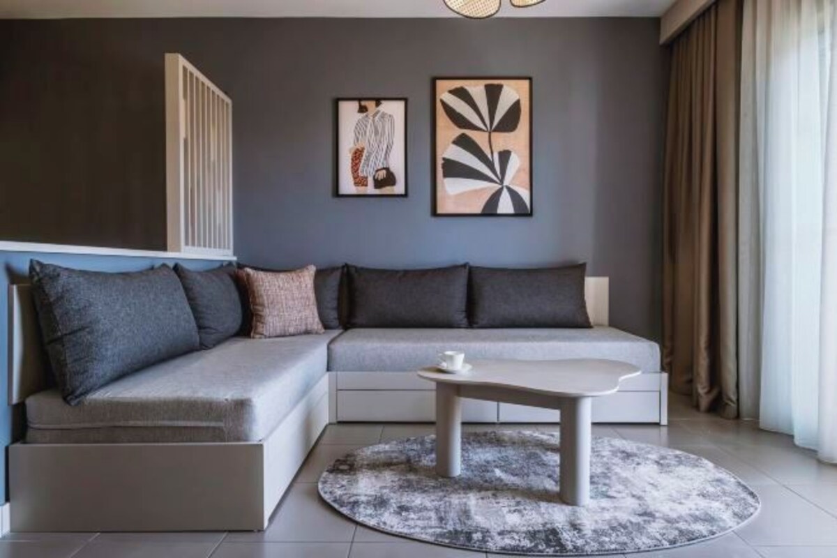 A modern living room with a sectional sofa, a coffee table, and artwork on the wall.