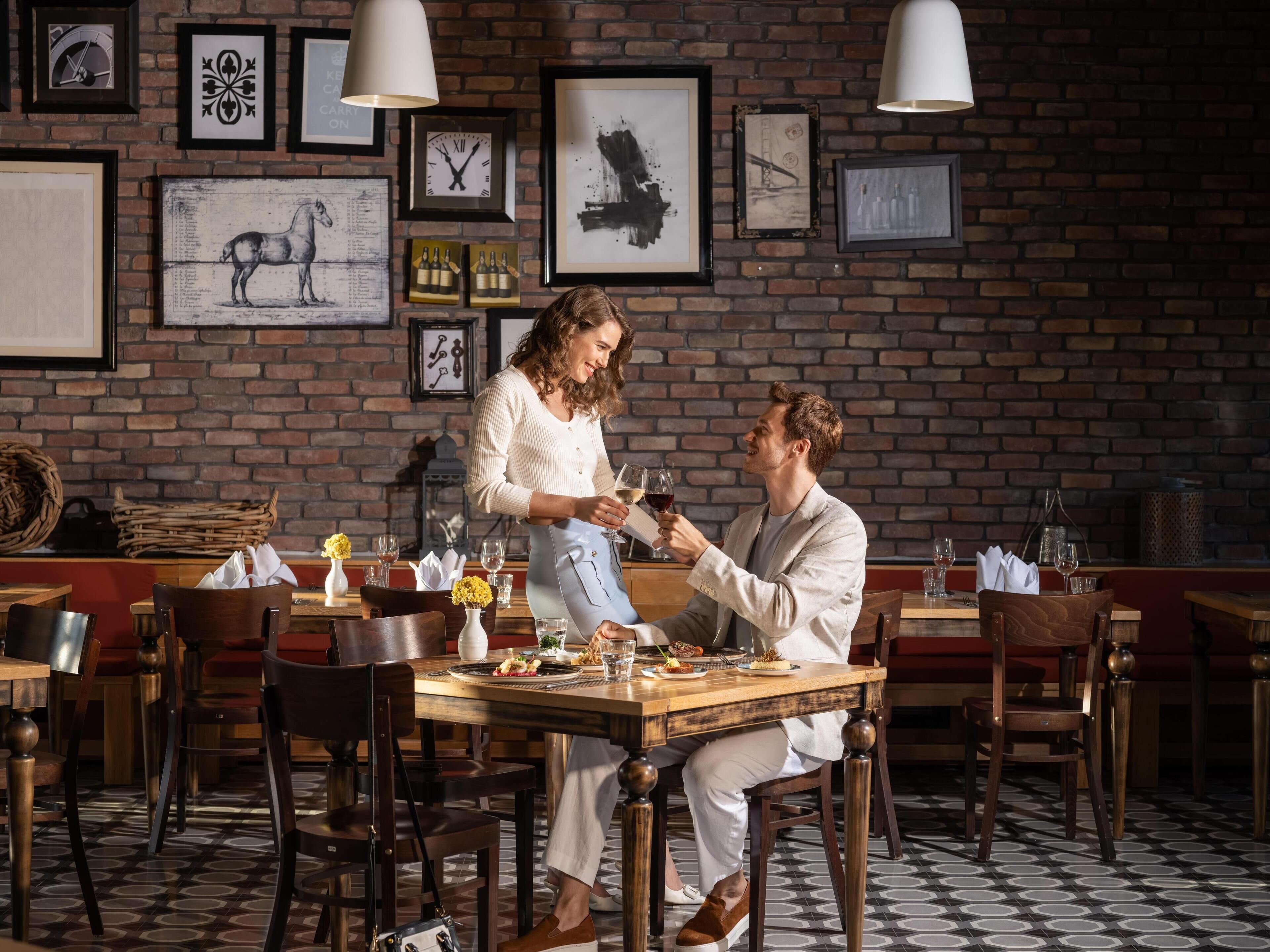 A restaurant with brick walls, framed artwork, and wooden tables and chairs.