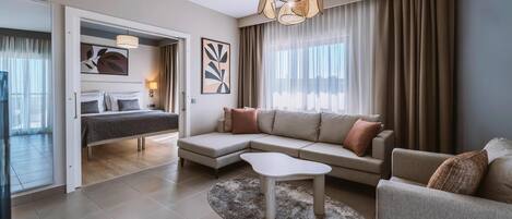 Una habitación de hotel moderna con una cama, un sofá, una mesa de centro y un ventanal con cortinas.