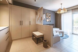 Habitación de hotel moderna con un armario grande, un taburete pequeño, una mesa redonda y una lámpara decorativa.