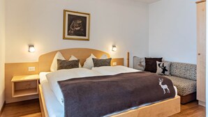 Ein Schlafzimmer mit Bett, Nachttischen, einer Couch, einem gerahmten Bild und Wandleuchten.