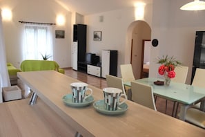Relax in this stylish living area with a long dining table, comfortable sofa, and modern entertainment unit.