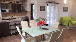A modern kitchen with white cabinets, a dining table with chairs, and a vase with flowers.