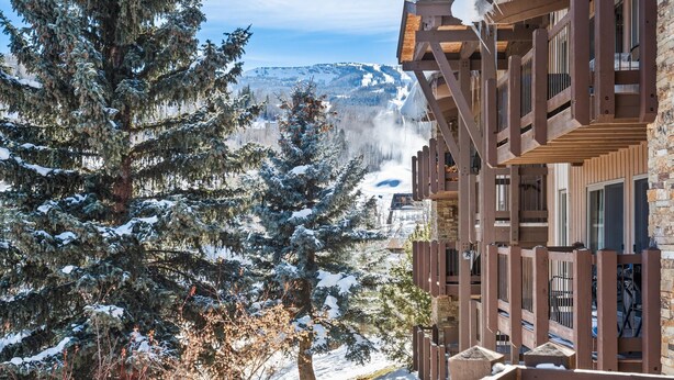 Paisaje nevado de montañas con un edificio de madera que tiene balcones y ventanas amplias.
