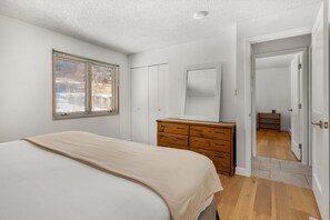 A bedroom with a bed, a dresser, a mirror, and a window.