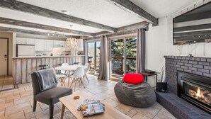 Amplia sala de estar con chimenea, una mesa de comedor y una cocina al fondo.