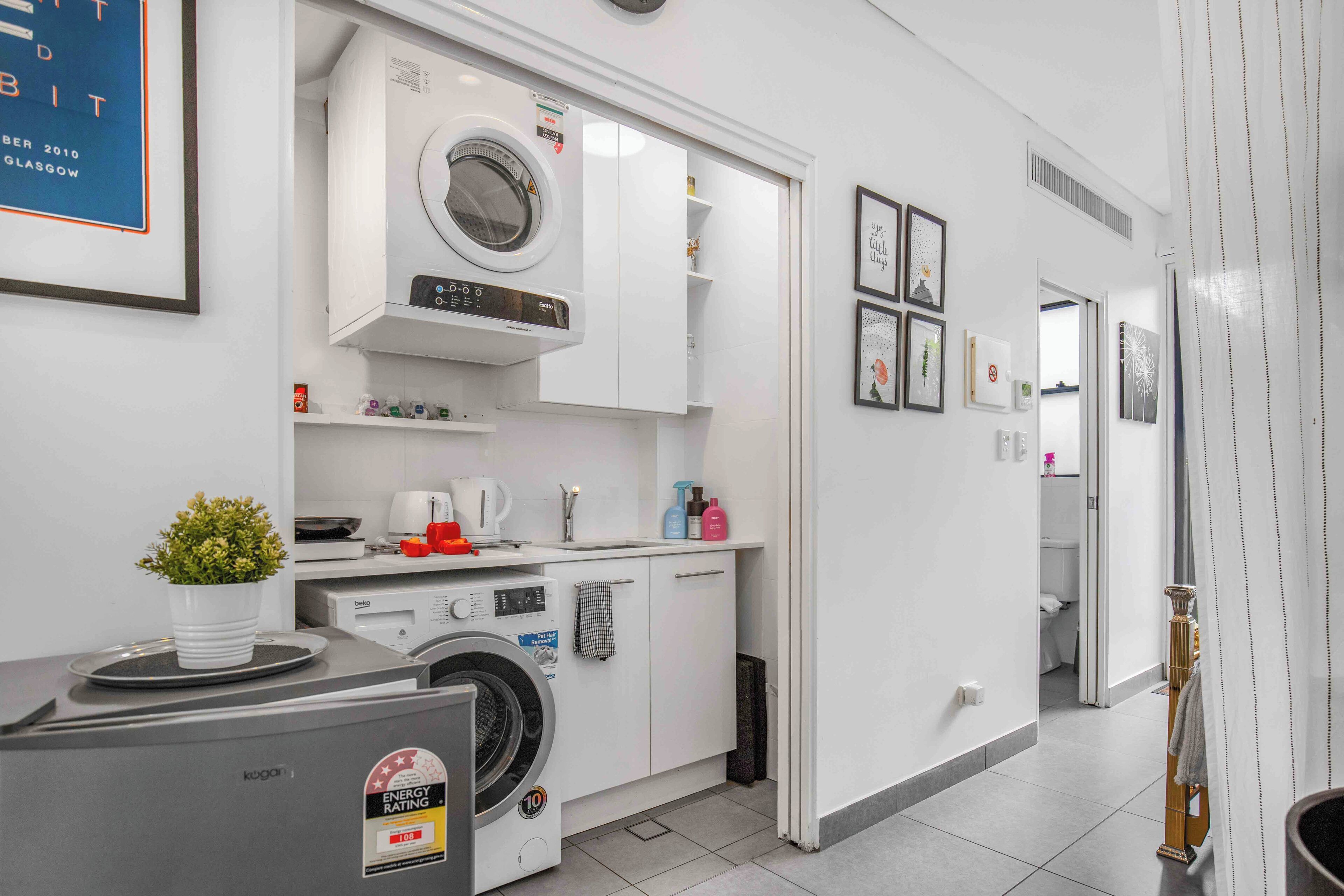 A modern kitchen with a built-in washing machine, a coffee machine, and a kettle.