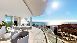 Un balcon moderne doté d’une balustrade en verre incurvée, offrant une vue imprenable sur la côte.