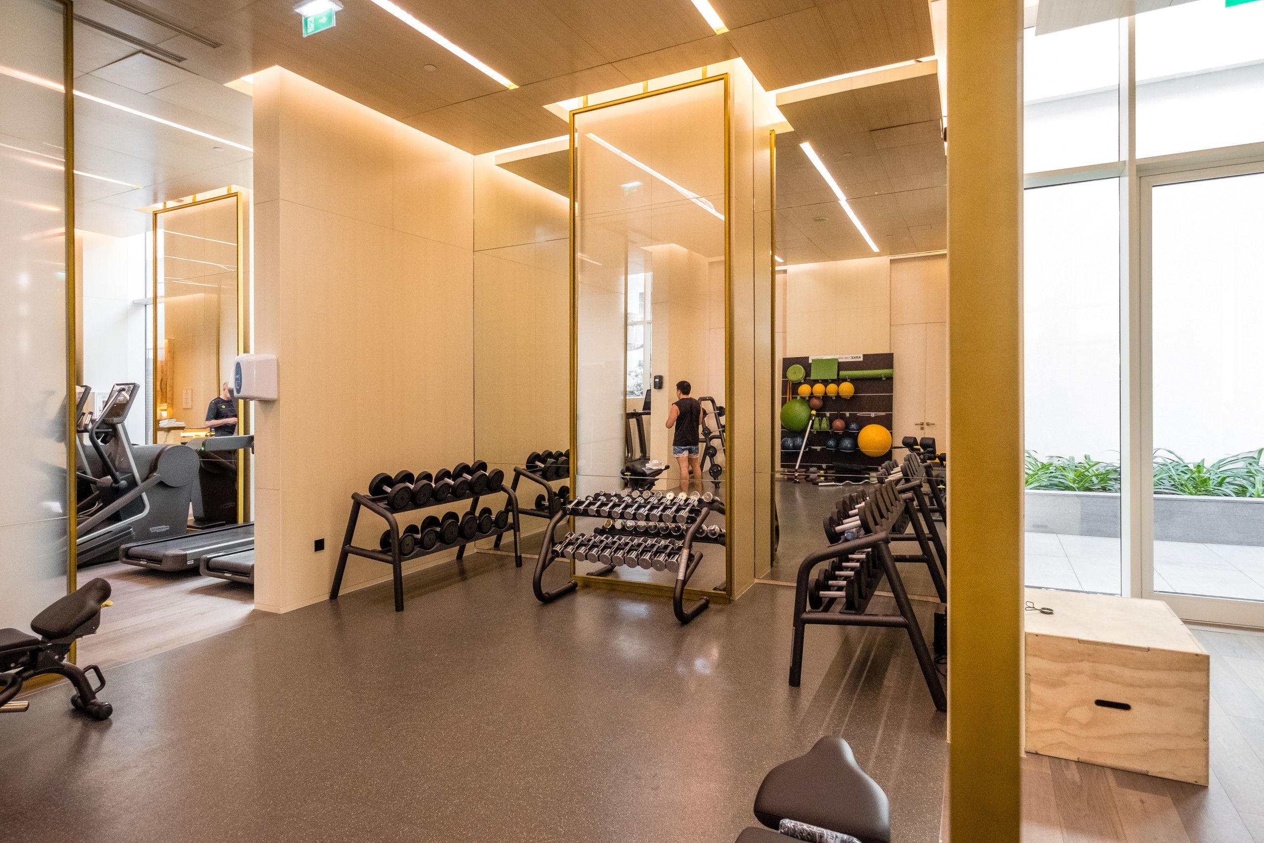 A modern gym with exercise equipment, a mirror, and a view of the outdoors.