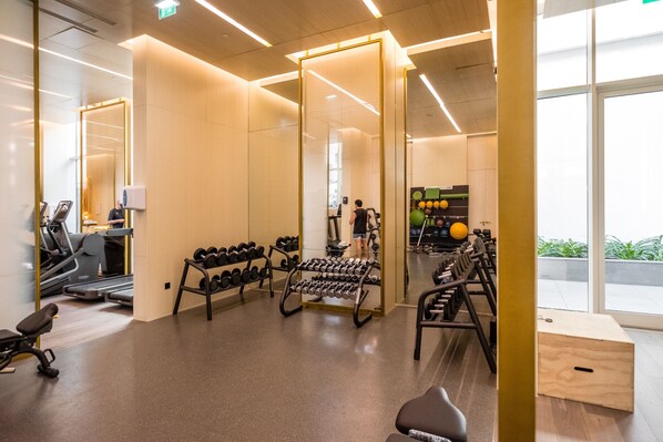 Une salle de sport moderne équipée de matériel d’exercice, d’un miroir et offrant une vue sur l’extérieur.