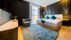 Ein modernes Schlafzimmer mit einem großen Bett, einem kleinen Sessel, einem Nachttisch und einem großen Fenster.