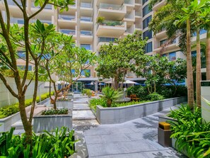 A modern building with multiple floors, outdoor seating areas, and lush greenery.