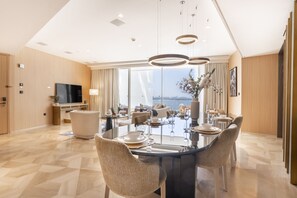 A modern dining area with a glass table, woven chairs, and a view of the city.